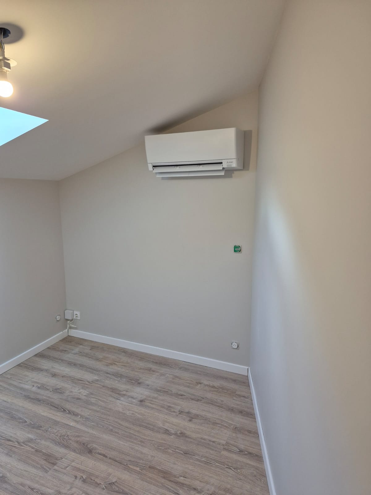 Climatisation murale Mitsubishi installée dans un appartement rénové avec parquet